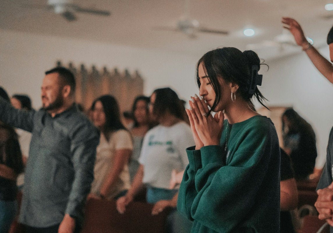 people in prayer and worship with congregation