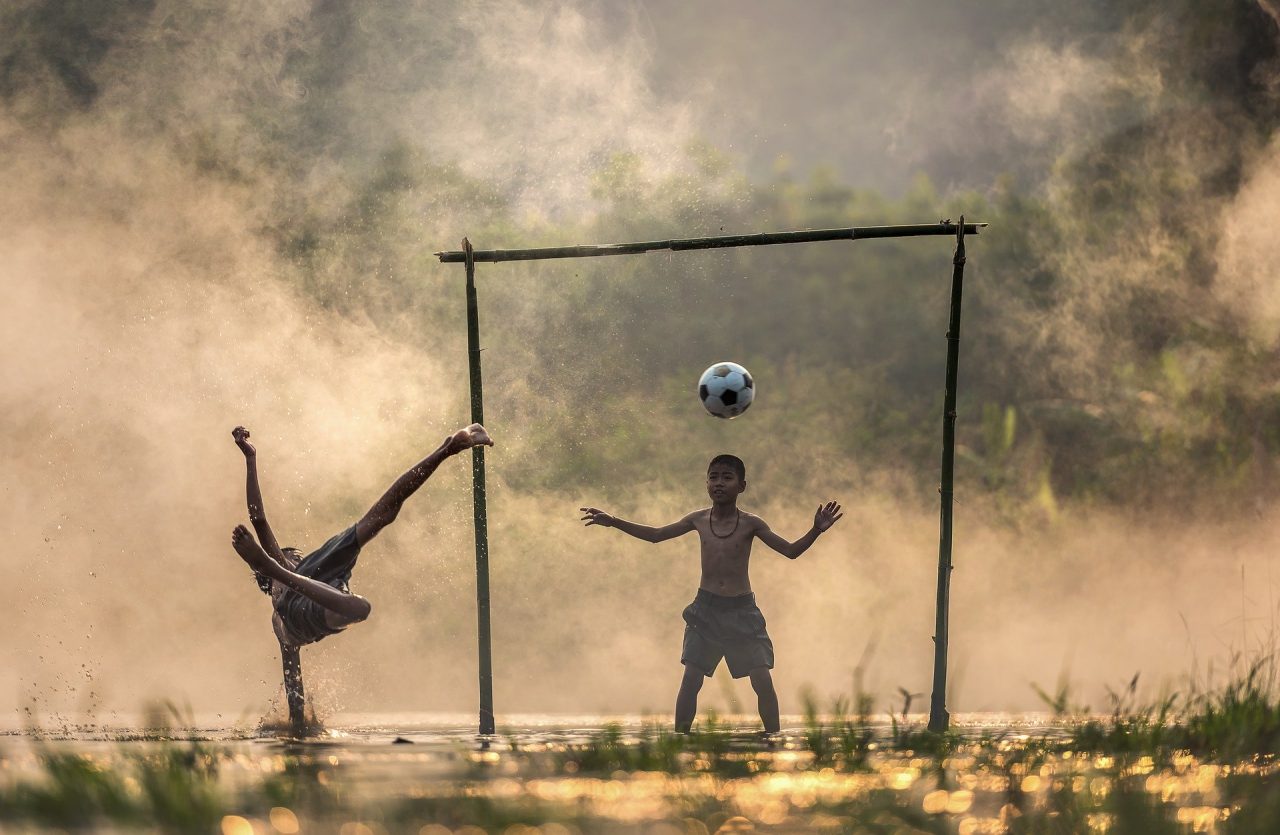 crianças jogando futebol na rua