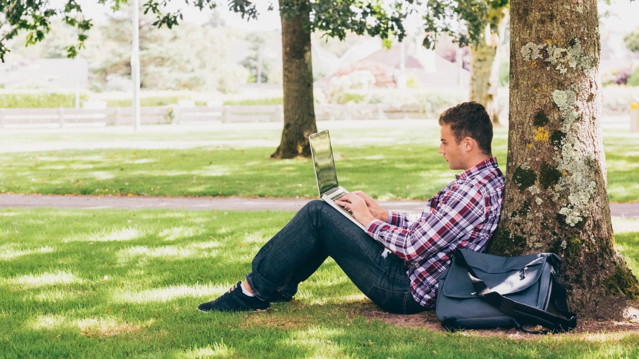 Young student using laptop outside