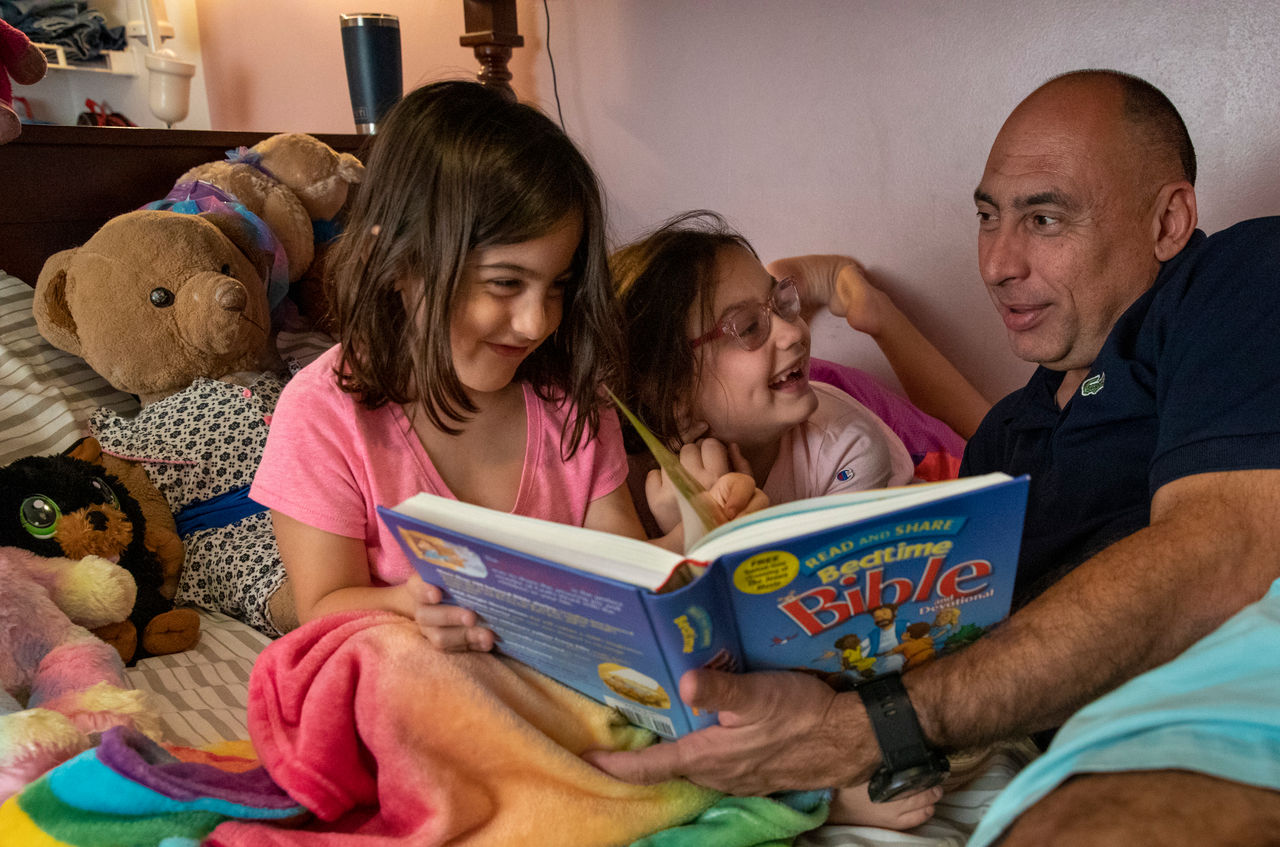 Father reading to daughters