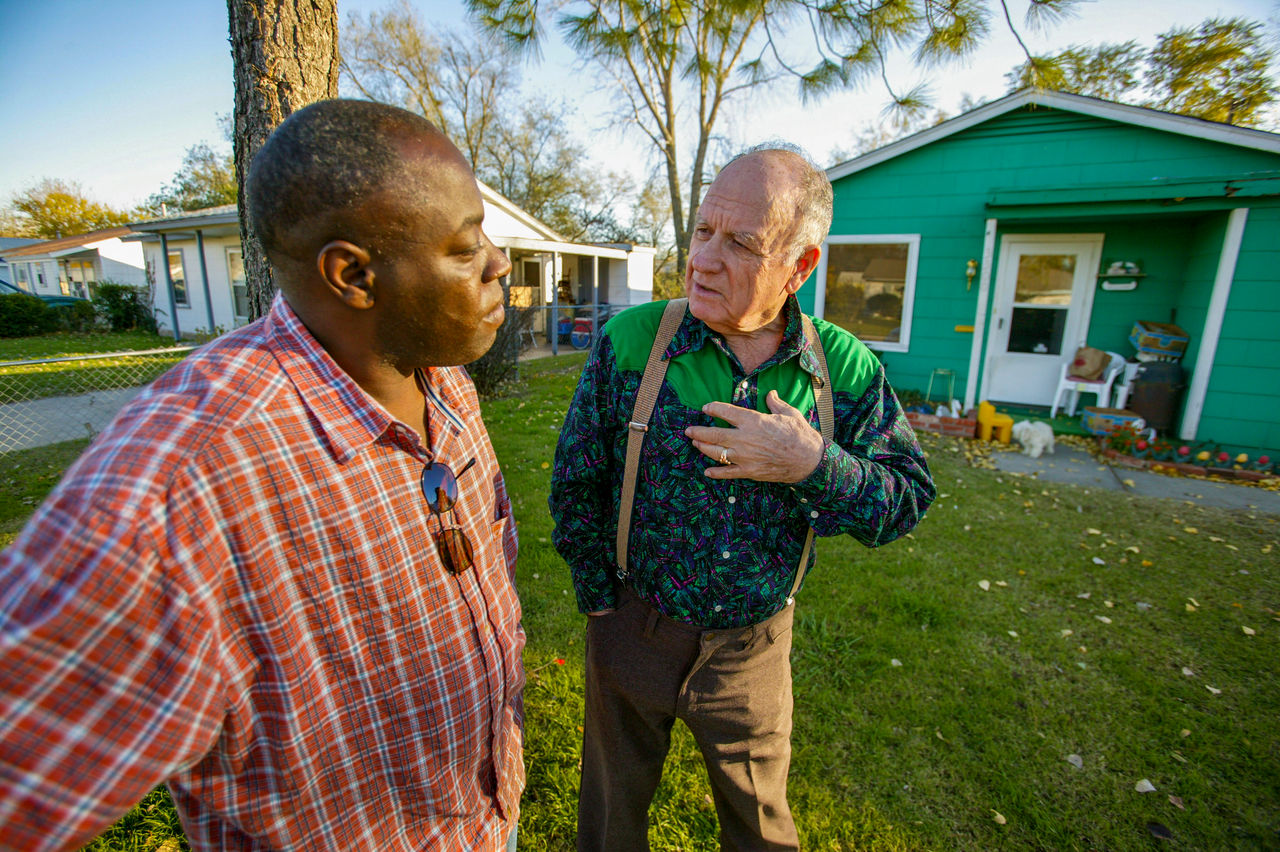 two men in front of green house