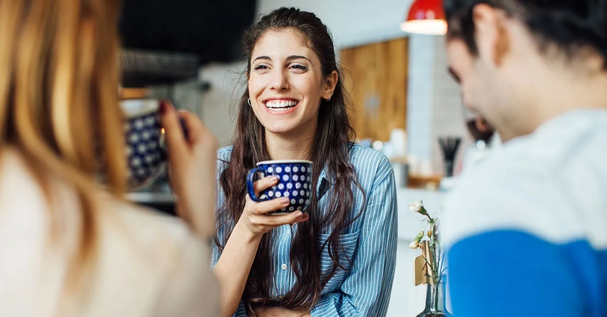People talking and smiling while drinking coffee.