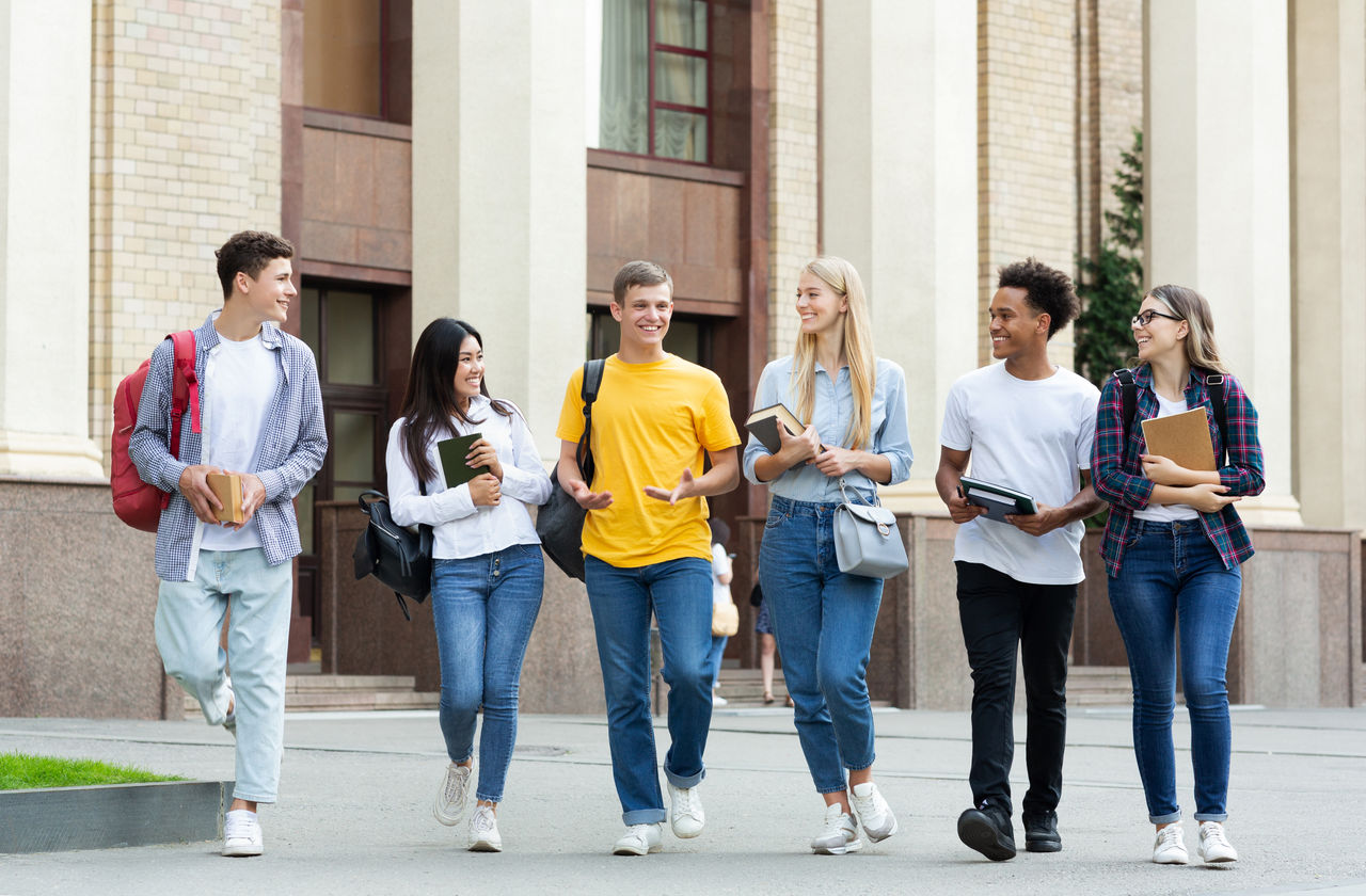 University life. Classmates walking outside and talking about passed exams